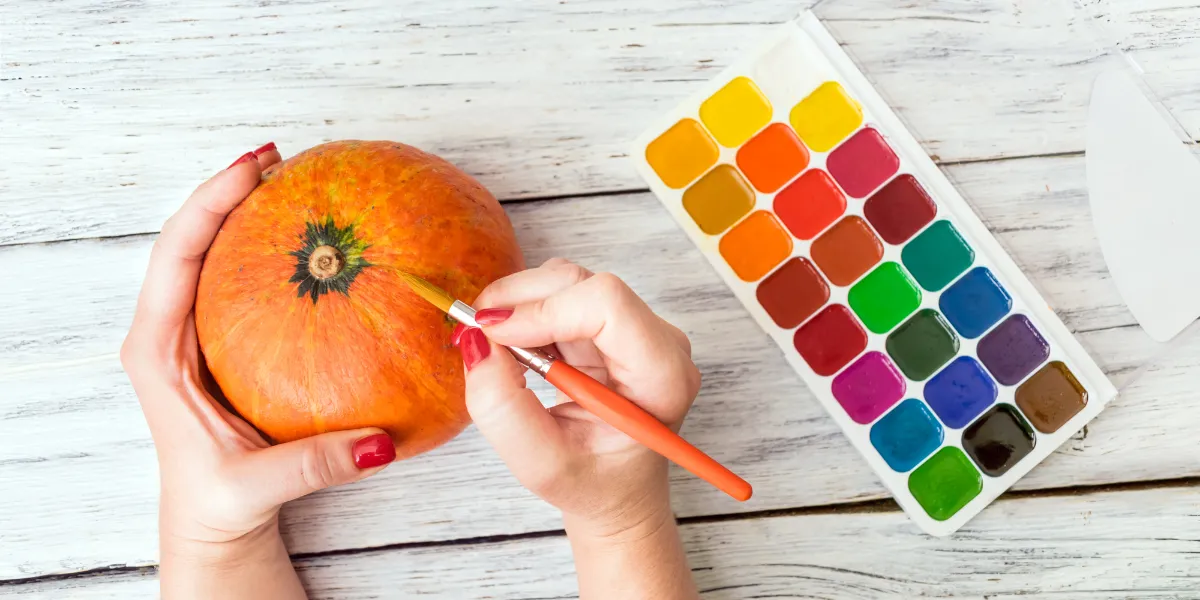 Höstpysselmaterial med färgglada löv, kottar och halloweenmasker för kreativa projekt under hösten.